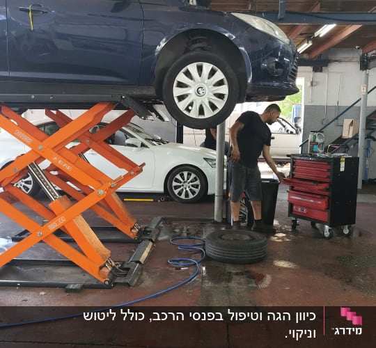 רכב על מעלית במוסך עם מכונאי ליד ארגז כלים
